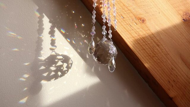 Selective focus on tear drop shape crystal rainbow maker suncatcher hanging in home. Good Feng Shui, Sha Chi energy flow concept.
