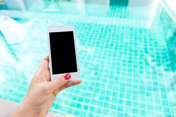 Girl hand holding smartphone over clean swimming pool, automatic control system, smart application for pool controler, summer outdoor day light