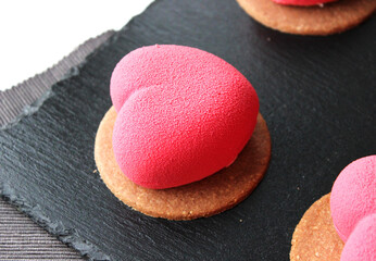 Pink macaroons in the shape of a heart on a black stone plate, a sweet gift for Valentine's Day