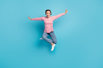 Fototapeta na wymiar Full size photo of young attractive girl happy smile jump up hands wings fly isolated over blue color background