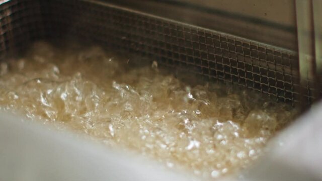 Delicious food deep frying in oil in a commercial metal fryer in a restaurant as an accompaniment to meals.