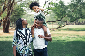 Happy black people family in garden with son playing airplane toy