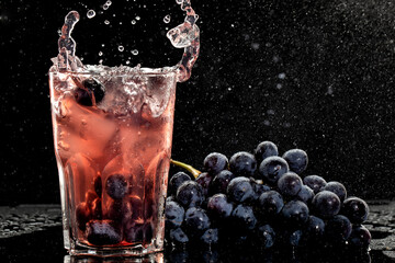Fresh grape juice and ice cubes on black background