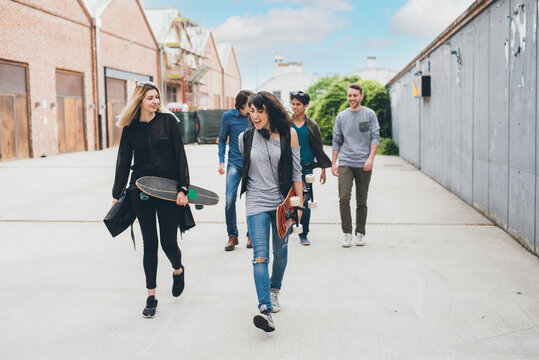 Group of friends skaters walking outdoors having fun chatting