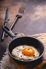 Fried egg in the pan on a dark rustic background. Still life- fast food. 