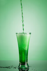 Green carbonated estragon lemonade flow into glass
