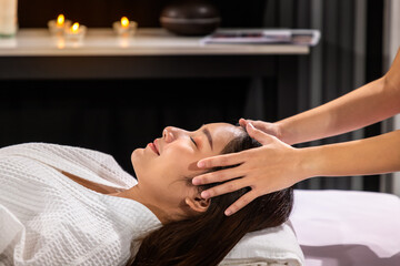 Fototapeta na wymiar Beautiful young Asian woman enjoy head massage in tranquil spa salon, with candle.