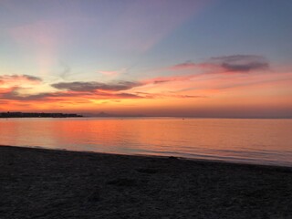 Obraz premium Atardecer con el cielo anaranjado y rosado en la playa cerca del mar