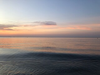 Fototapeta na wymiar Atardecer con el cielo anaranjado y rosado en la playa cerca del mar