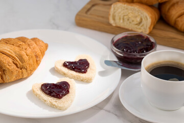 fresh croissants with jam and coffee on light background