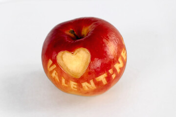 Apple with a heart carved in it with the inscription valentine