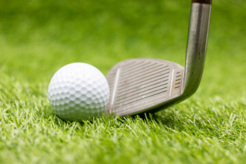 Golf ball and iron are on green grass