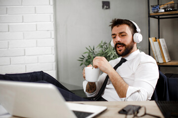 Attractive businessman in office. Young businessman with headphones singing at work