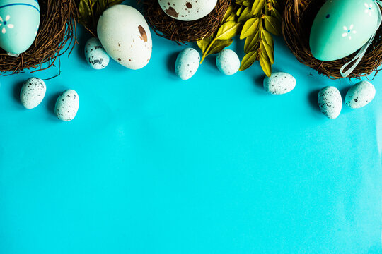 Painted Easter eggs and bird's nests decorations on a blue background