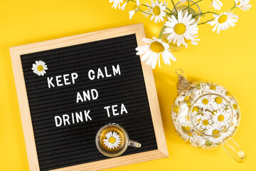 Keep calm and drink tea. Motivational quote on black letter board and herbal chamomile tea on yellow background. Concept inspirational quote of the day. Flat lay Top view