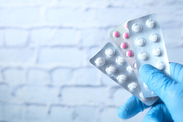 Close up of hand in latex gloves holding blister packs .