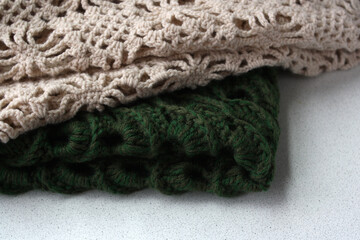 Crocheted scarves on a light background. There is room for text. Women's knitted shawls with a pattern. Handwork.
