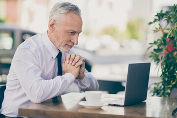 Photo of smiling cheerful mature worker man wear formal shirt drinking beverage cafeteria reading modern gadget outdoors city street