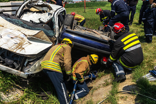 Firemen trying to release man from crashed car. There is a crashed cars in car accident.