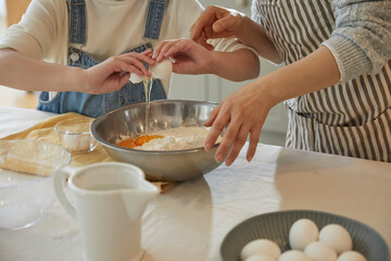 Happy adorable little child girl in apron enjoying cooking homemade pastry together with grandmother at home.