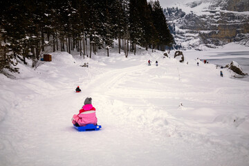 Children playing with sled in snowy mountain landscape