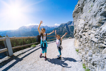 Children hiking on beautiful summer day in alps mountains Austria, resting on rock and admire...