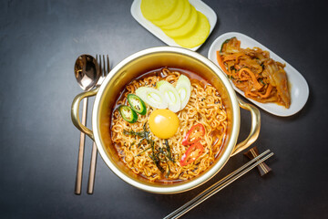 Korean traditional Ramyeon noodle  with egg yolk, chilli, kimchi in a traditional korean noodle pot, Spicy Korean Ramyeon instant noodle a traditional dish.