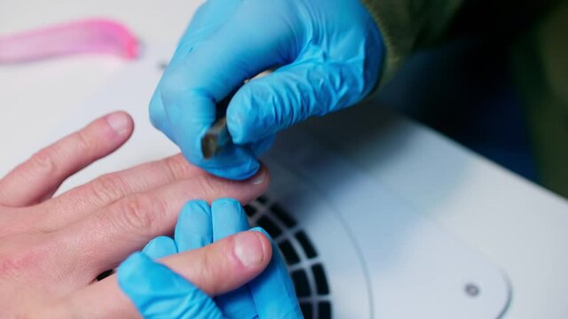 Manicurist uses metal nippers to remove dry skin of cuticle around nails. Processe of manicure.