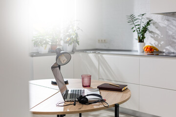 Working from home - a laptop and an organizer on a kitchen table with kitchen in the background.