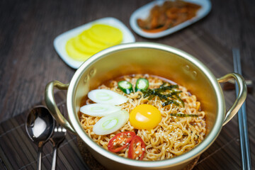 Korean traditional Ramyeon noodle  with egg yolk, chilli, kimchi in a traditional korean noodle pot, Spicy Korean Ramyeon instant noodle a traditional dish.