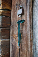 The simplest rustic door lock. A rusty padlock on a wooden door of an old rustic building.