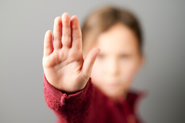 Obraz na płótnie Canvas Kind in einer roten Jacke streckt die Hand aus, zeigt fünf Finger und sagt Stopp