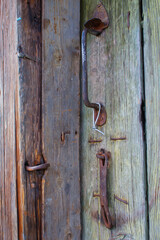 The simplest rustic door lock. A rusty padlock on a wooden door of an old rustic building.