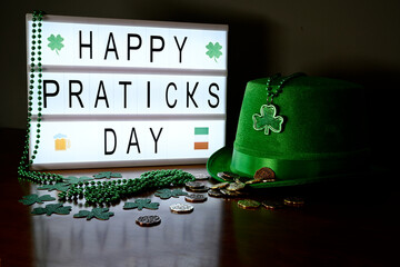 Concept of St. Patrick. Green hat, green necklaces and clovers, lucky coins and lightbox message with letters Happy st Patrick's day.