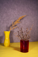 Dried natural lavender in a plastic red vase. Dry spikelet in a yellow ceramic vase. Withering, aging, sadness and death concept.