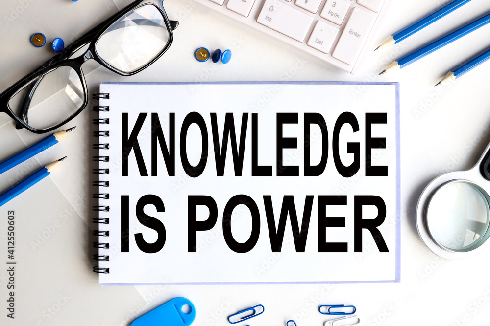 Poster knowledge is power. text on white notepad paper on a light background near the keyboard and glasses.