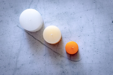 Velas aromáticas de distintos tamaños sobre una pared de concreto visto desde arriba