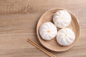 Steamed buns stuffed with minced pork and chopsticks on wooden table, Asian food