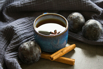 Simple still life in blue colors with ceramic cup and fresh plums. Dark grey background. 
