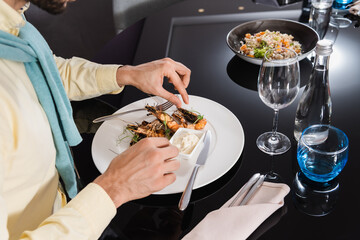 Cropped view of man sitting near delicious shrimps on plate in hotel room