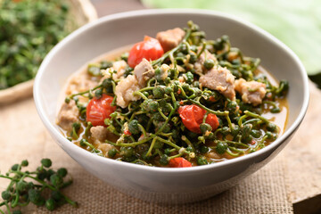 Northern Thai food (Kaeng Sa Lae), Spicy soup Broussonetia Kurzii with pork and tomatoes in a bowl on wooden background, Seasonal food in North Thailand