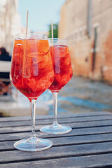 Two glasses of Spritz Veneziano cocktail served near the Venetian canal.  Popular italian summer aperitif drink. Venice background.