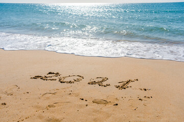 2021 year sign hand written sandy beach sunny outdoors background.