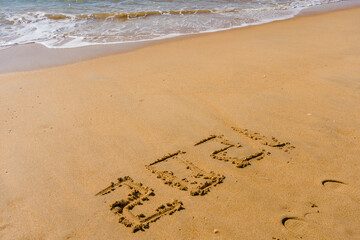 2021 year sign hand written sandy beach sunny outdoors background.