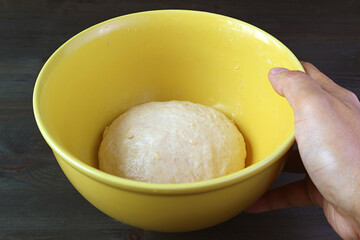 Hand placing a bowl of kneaded dough on the table to let it rises before baking