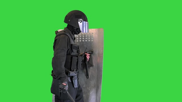 Heavily armored policeman with a shield and a baton walking on a Green Screen, Chroma Key.