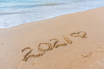 Fototapeta na wymiar 2021 year and love heart sign hand written sandy beach outdoors seascape background.