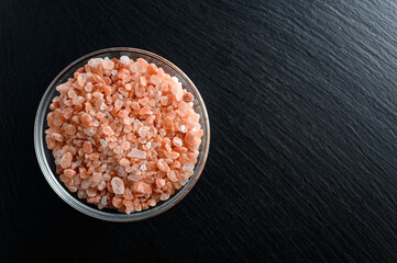 Glass bowl of himalayan salt on black background with empty space