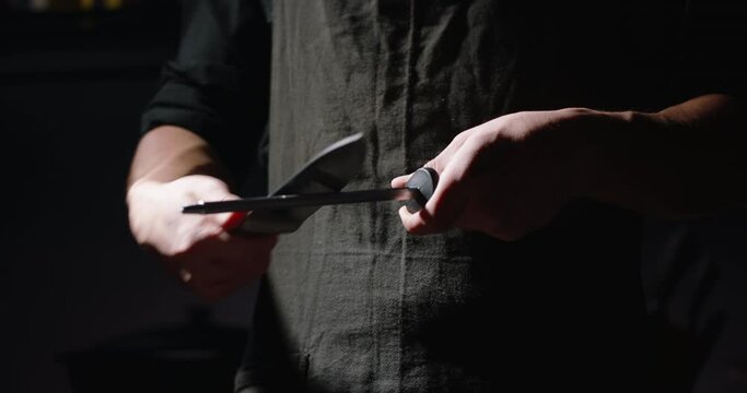 Close-up shot of chef sharpens knife for cooking, chef preparing his knife, 4k footage.