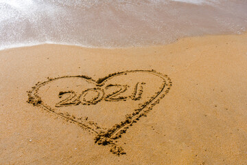 2021 year and love heart sign hand written sandy beach outdoors seascape background.
